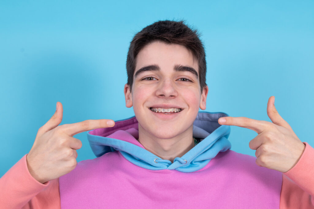 teenager pointing at teeth smiling