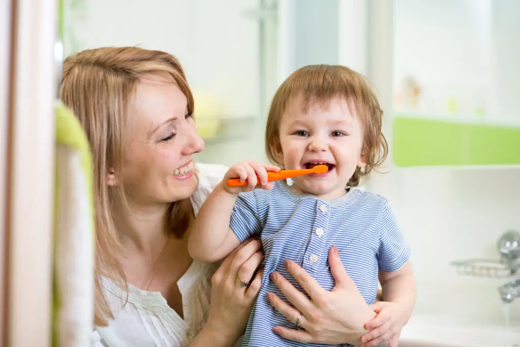 mom looking at baby brushing teeth
