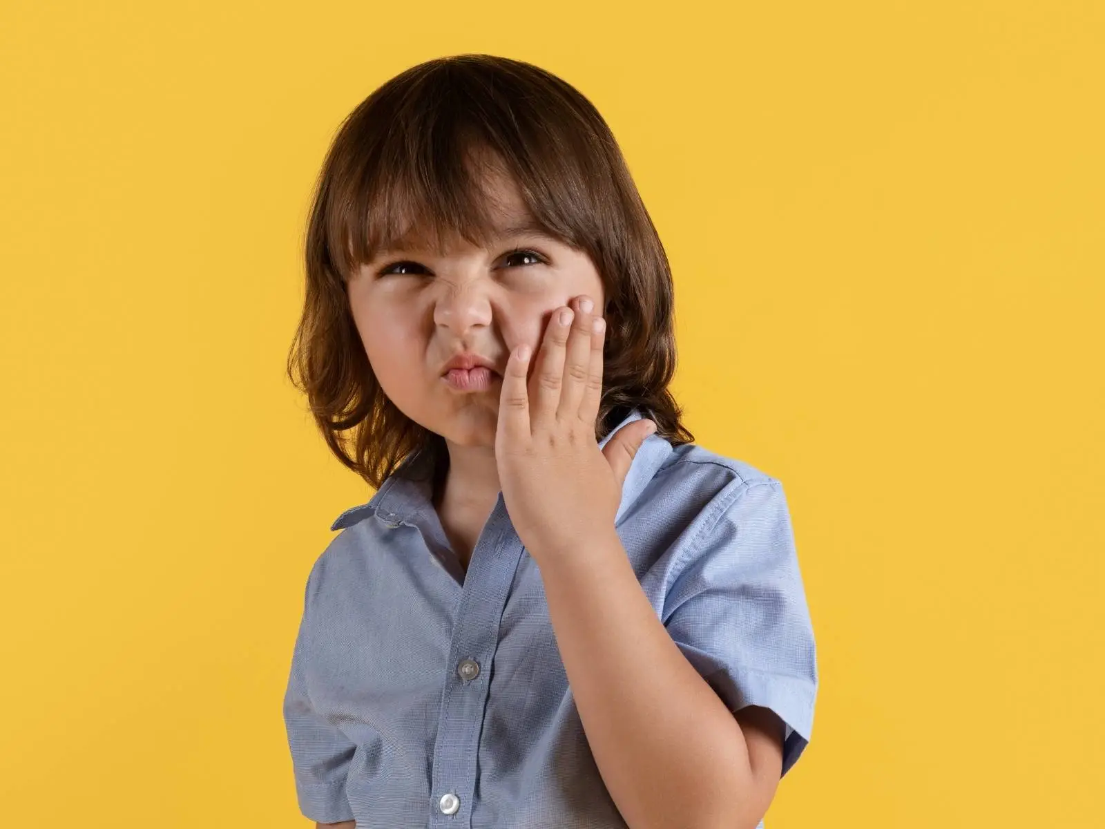 boy holding face in tooth pain