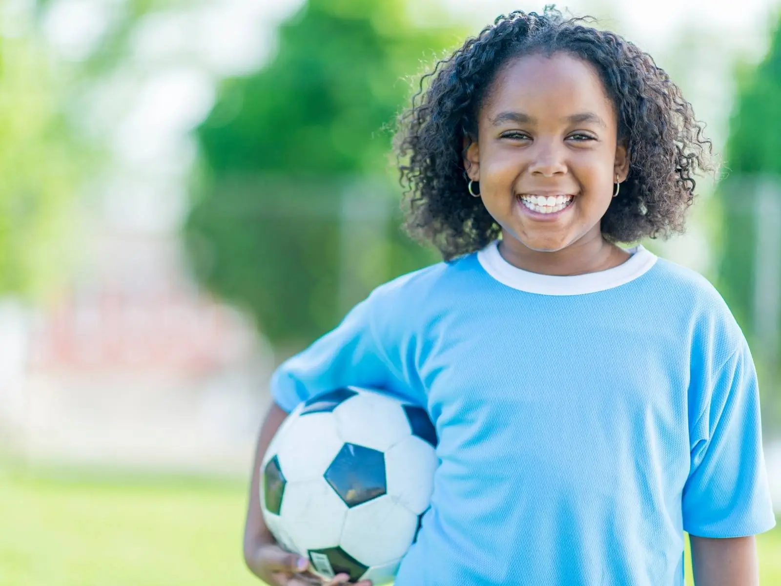 little girl smiling holding a soccer ball